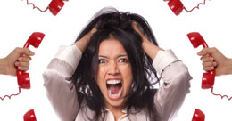 A stressed woman at work pulling her hair surrounded by telephones which links to Dr Gowrisunkur's top tips to deal with stress at work